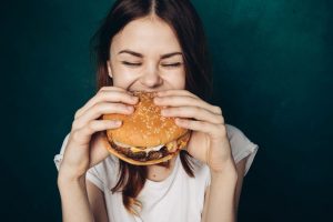 Teenage girl eating large burger