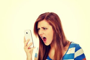 Angry young female teenager looking at her phone.