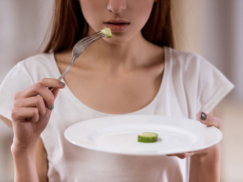 Teenager suffering with low self-worth eating a plate of cucumber