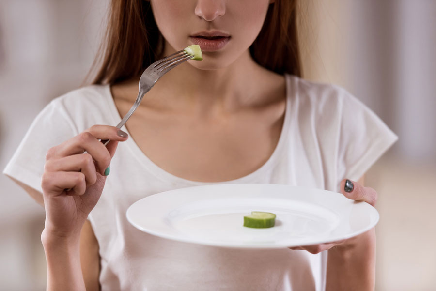 Teenager suffering with low self-worth eating a plate of cucumber