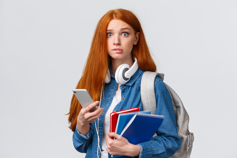 Female student with long ginger hair carrying books