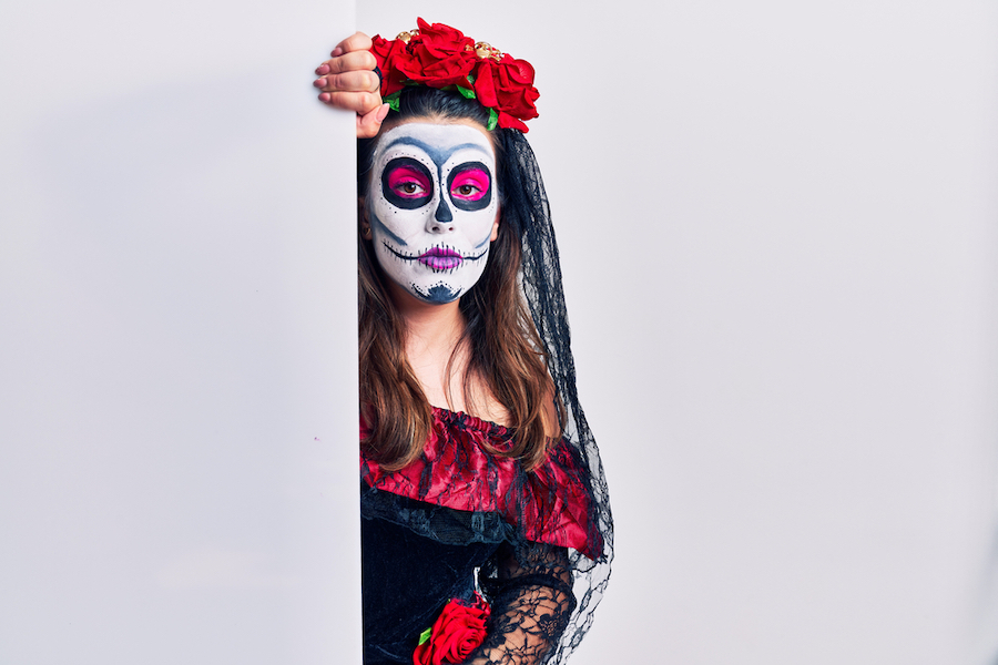 Young woman wearing day of the dead custome holding blank empty banner relaxed with serious expression on face. simple and natural looking at the camera.