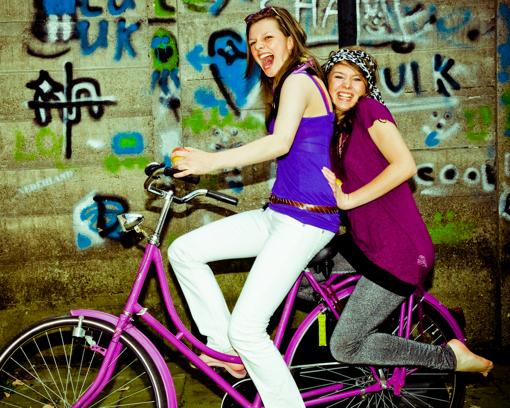 Two teenage girls riding on a bike